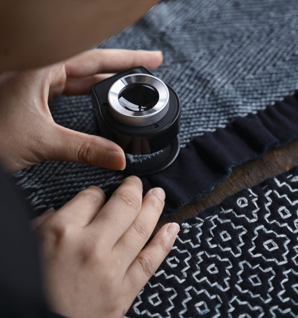 Close-up of hand examining sashiko stitching pattern