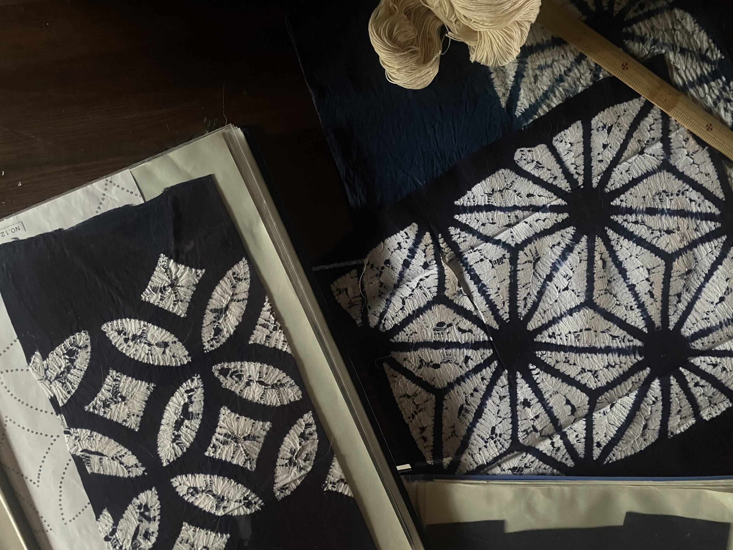Indigo-dyed cloths with white shibori patterns, including an asanoha pattern.